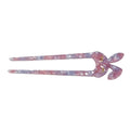 A tortoiseshell hair claw clip in a pink and purple marbled pattern with small gold butterfly accents, shown on a plain white background.